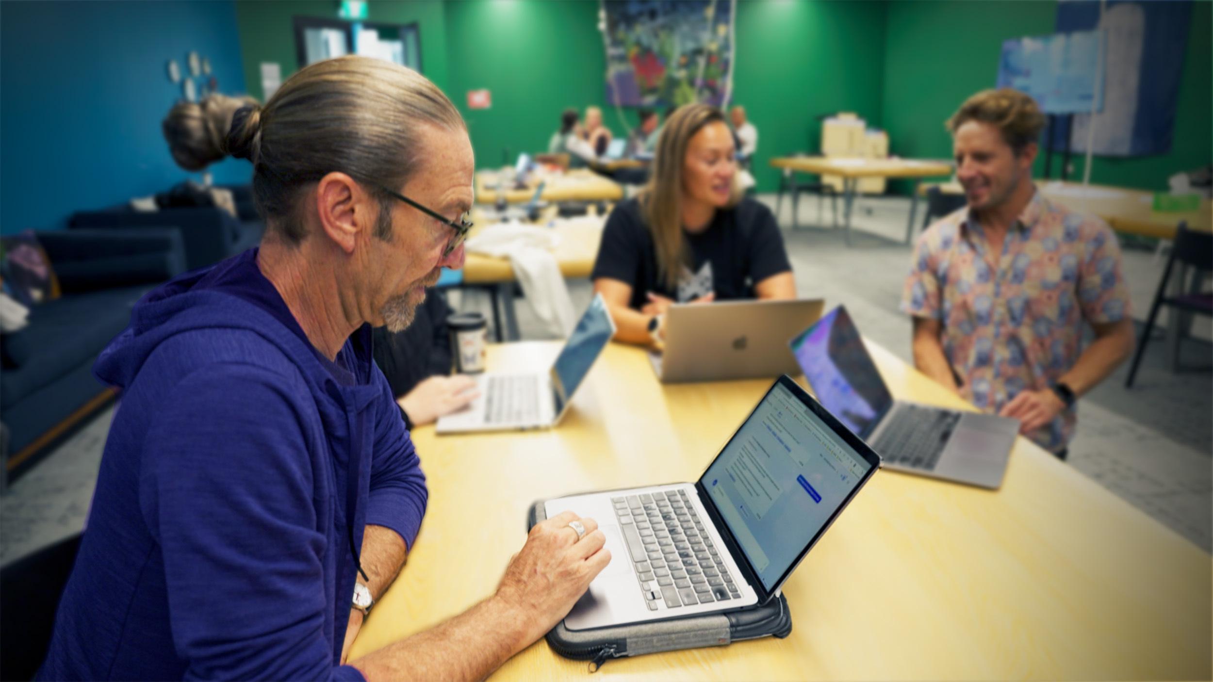 Man works at laptop in classroom environment