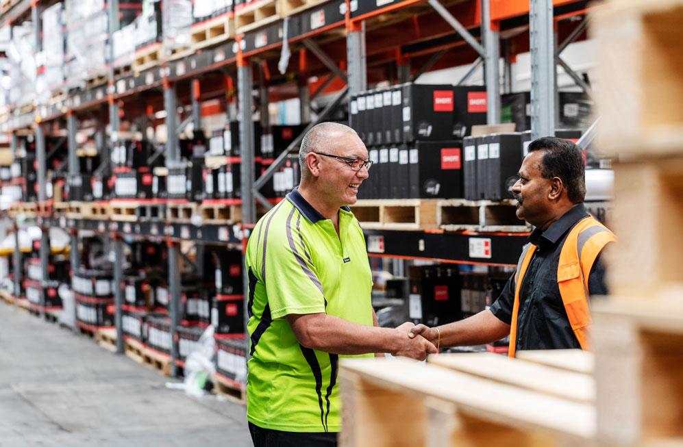 Two men shaking hands in a warehouse.