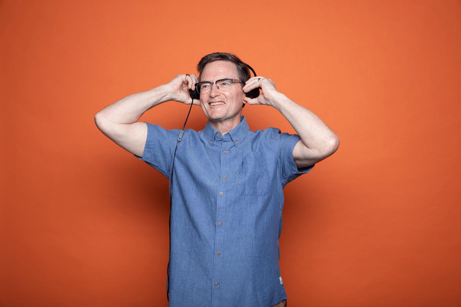 A person adjusting their headphones and smiling